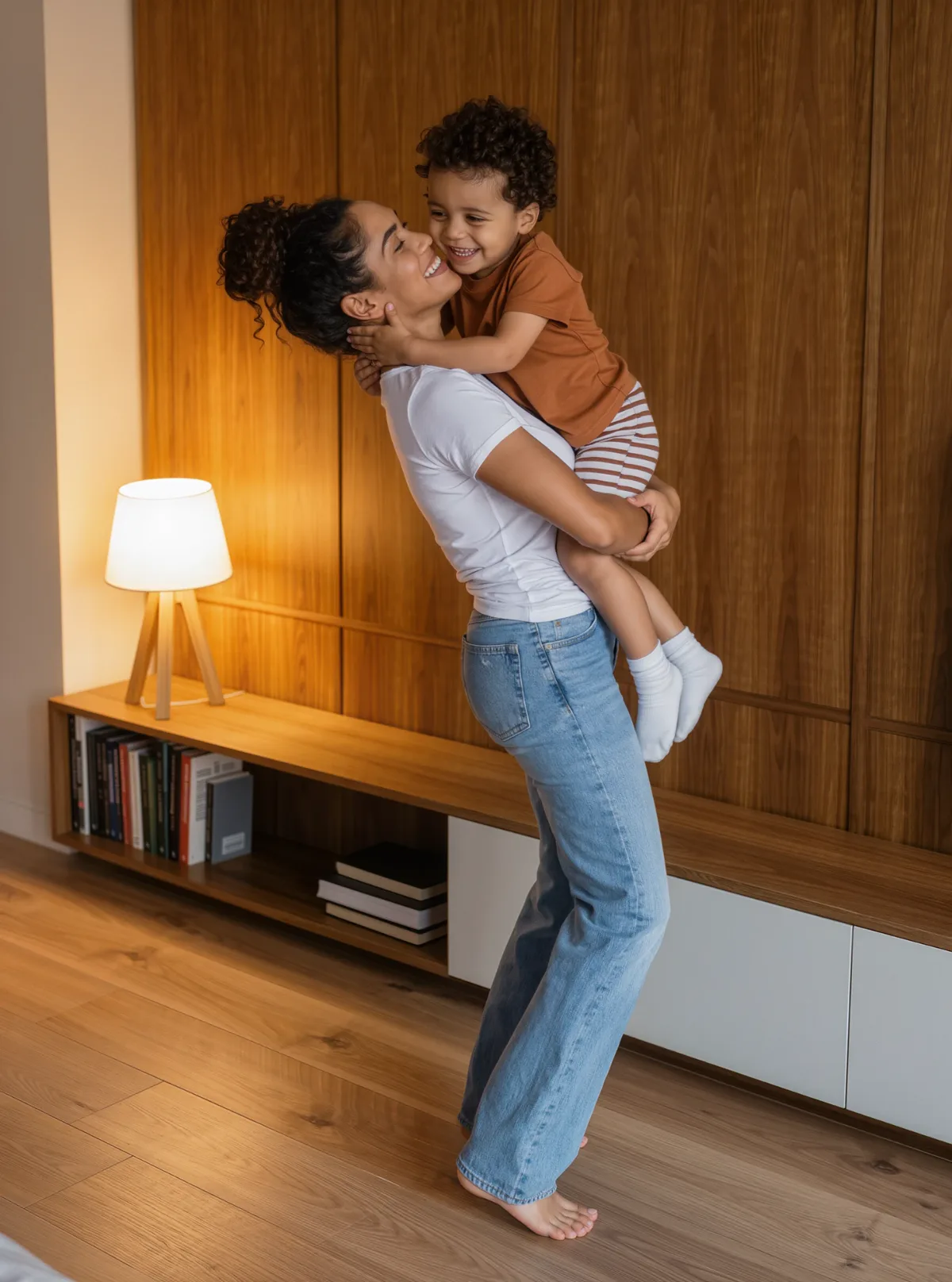 Mãe segurando o filho no colo, os dois rindo, em uma sala arrumada