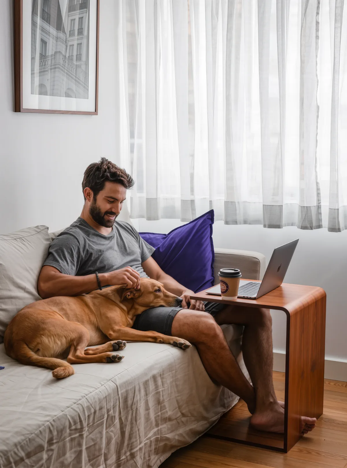 Homem relaxado no sofá com um cachorro no colo, em uma sala limpa e clara